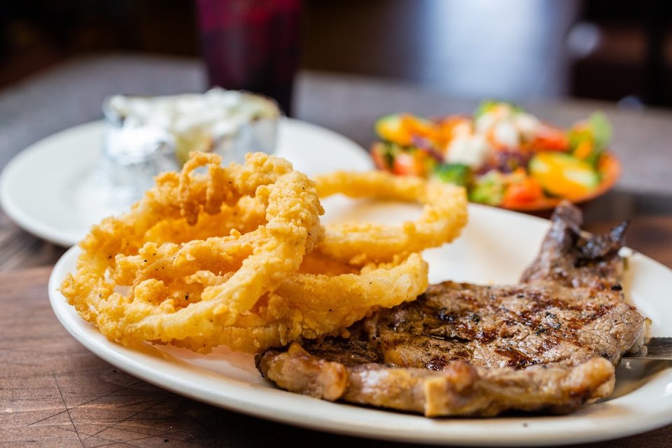 Plated steak with golden fries on a white plate.
